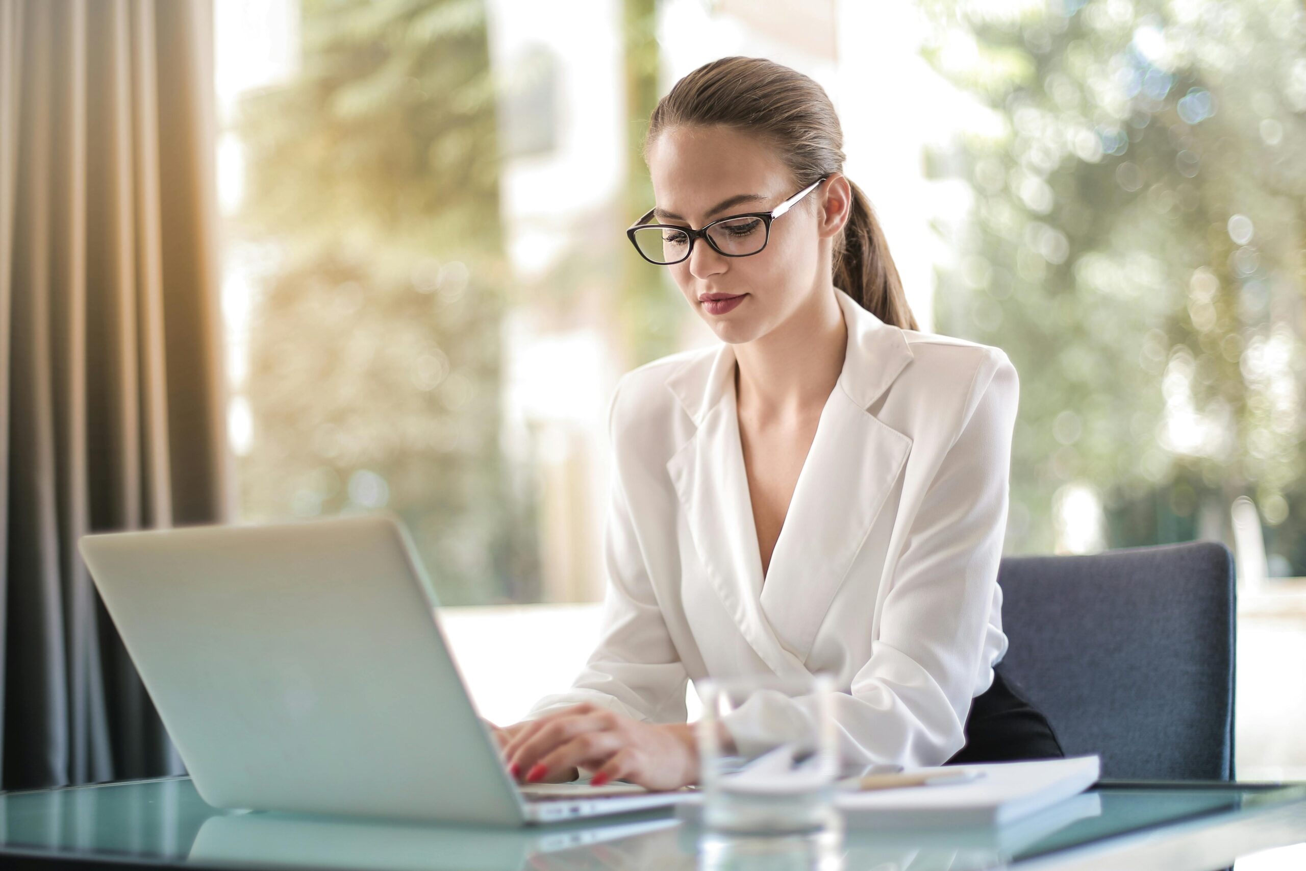 Home Confident businesswoman using a laptop at her desk, focused on her work.